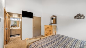 A bedroom with a bed, a dresser, a television, and a door leading to a bathroom. - Walton Creek Condo 34 | Mountain Views, Hot Tub and Bus Access (Steamboat Springs)