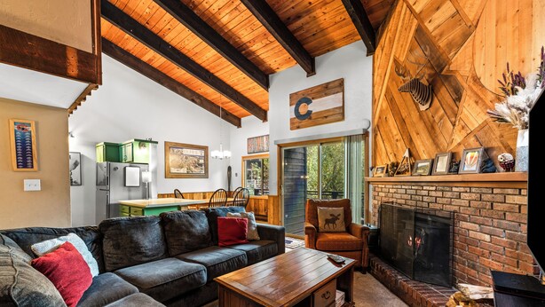 Ein gemütliches Wohnzimmer mit Kamin, einer Eckcouch und einem Essbereich mit grüner Arbeitsplatte.