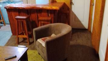 Ein Zimmer mit Esstisch, Stühlen, einer Couch und einer Küchenzeile im Hintergrund.