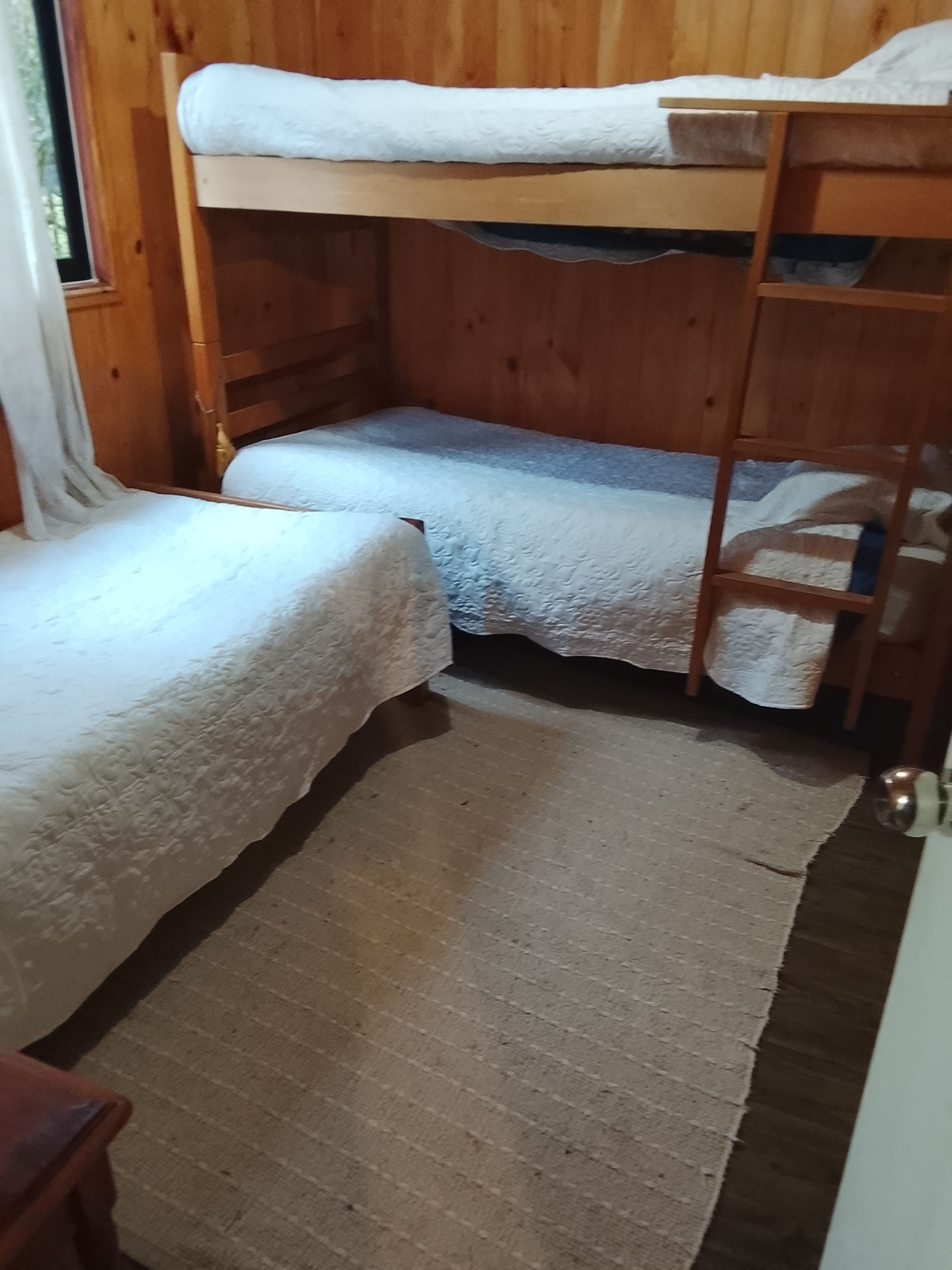 Habitación con literas, piso de madera y ventana.