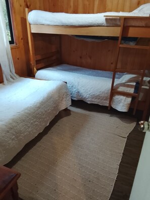 A bunk bed room with a wooden floor and a window.