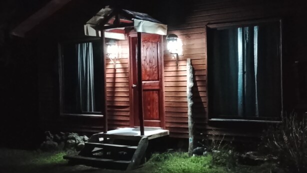 Un bâtiment en bois doté d’un porche et d’une porte, éclairé par un éclairage extérieur.