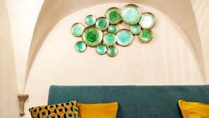A room with a green sofa, a patterned pillow, and a wall-mounted decorative plate arrangement. - In the Heart of Florence · 4 Min to Duomo & David (FIRENZE)