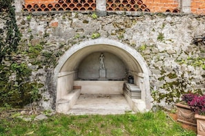 A stone structure with a statue, a small platform, and steps leading up to it. - Villa with natural spring amid Lucca vineyards (Lucca)