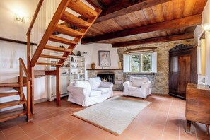 A rustic interior with a wooden staircase, white sofas, a fireplace, and a stone wall. - Villa with natural spring amid Lucca vineyards (Lucca)