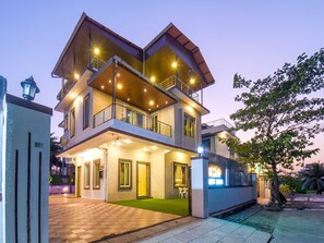 A multi-story residential building with a balcony, a covered entrance, and a well-lit exterior. - Nakshatra Villa by Palette Homes 4bhk (Mawal)