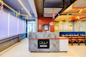 A reception area with a marble counter, a seating area with blue upholstered benches, and a wall with framed artwork.