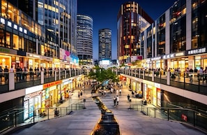 A bustling urban shopping area with modern buildings, a central water feature, and pedestrian walkways. - Siye Serviced Residence (Beijing)