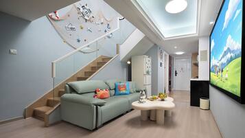 A modern living room with a sofa, a coffee table, a TV, and a netted play area on the wall.