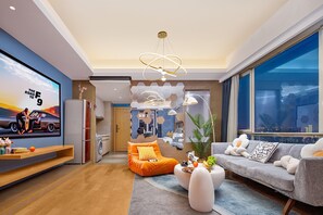Uma sala de estar moderna com uma televisão grande, área de estar e vista para a cidade.