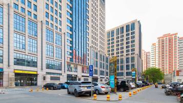 A city street with tall buildings, parked cars, and a pedestrian crossing.