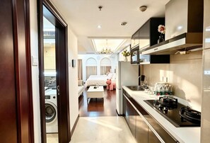 A modern hotel room with a kitchenette, a bed, and a view of the cityscape. - Siye Serviced Residence (Beijing)