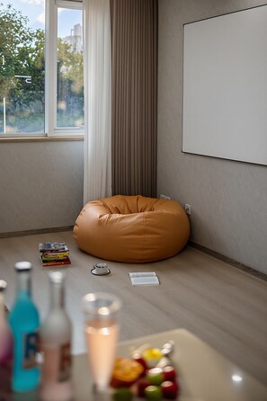 Quarto com poltrona de saco de feijão, lousa e janela com cortinas.
