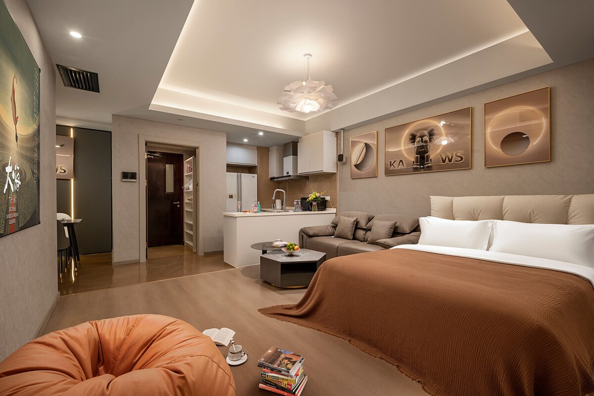 Quarto de hotel moderno com uma cama grande, um sofá, área de refeições e cozinha.