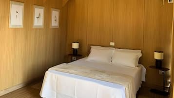 Un dormitorio con una cama grande, paredes de madera y tres cuadros en la pared.