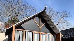 A small, single-story building with a sloped roof, large windows, and a balcony. - Chales Entre Vinhas (Canguera)