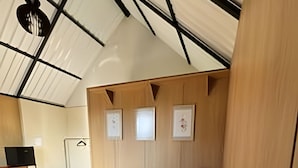 A modern bedroom with a large bed, wooden paneling, and a desk with a chair. - Chales Entre Vinhas (Canguera)