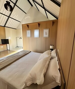 Un dormitorio moderno con una cama grande, paneles de madera y un escritorio con silla.