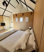 Quarto moderno com uma cama grande, painéis de madeira e uma escrivaninha com cadeira.