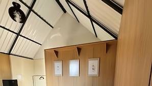 A modern bedroom with a large bed, wooden panel walls, and a skylight. - Chales Entre Vinhas (Canguera)