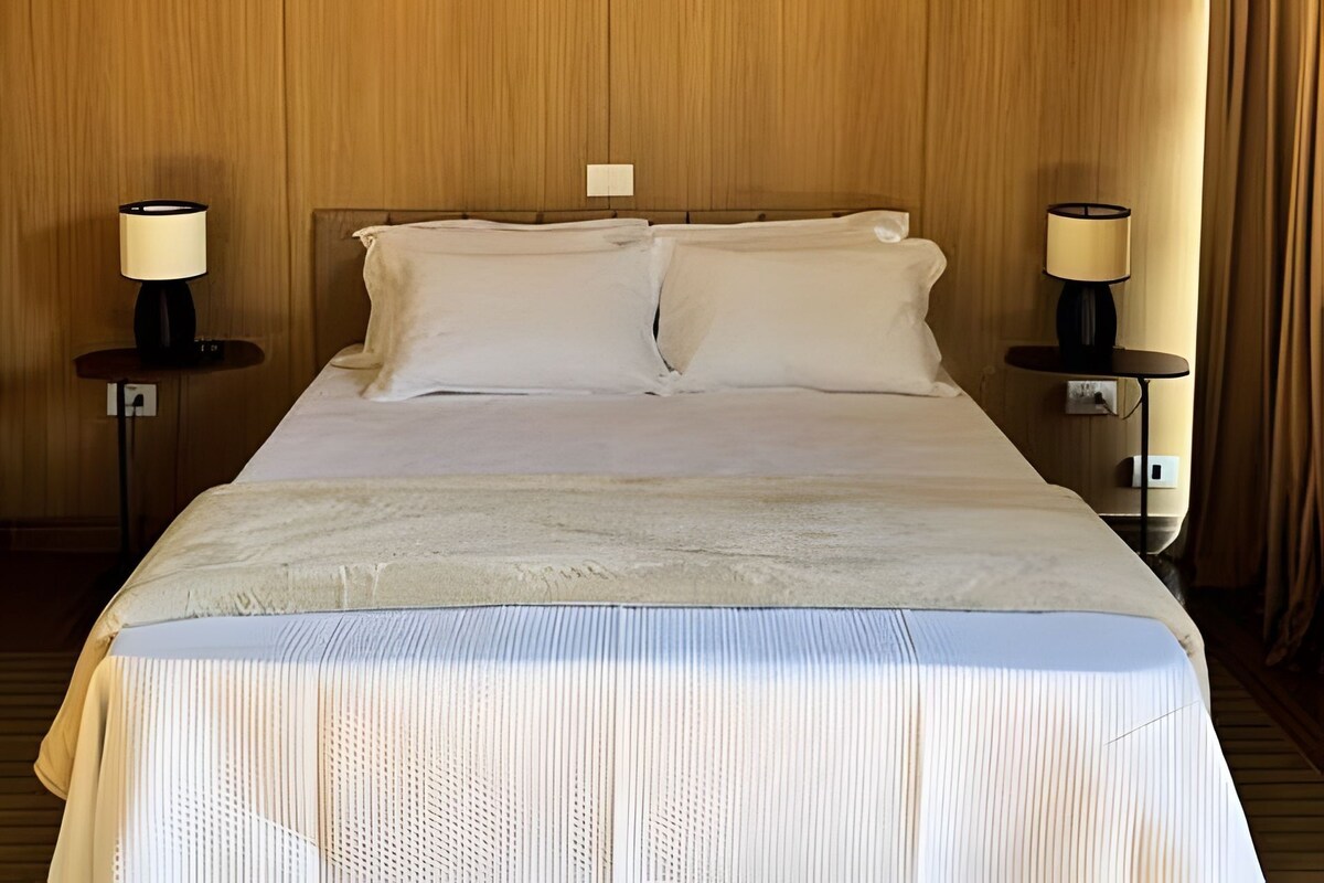 Una habitación de hotel con una cama, dos mesitas de noche y lámparas.