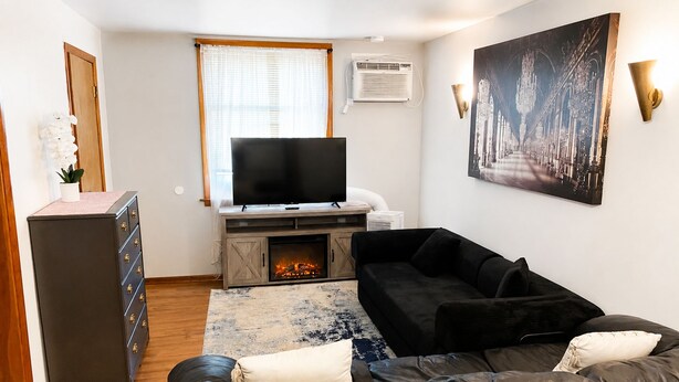Ein Wohnzimmer mit Kamin, Fernseher, einer Couch und einem Wandbild.