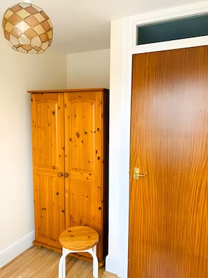 Ein Zimmer mit einem Holzschrank, einer Holztür und einem Hocker.