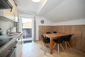 Una cocina compacta con comedor, una mesa de madera y sillas negras.
