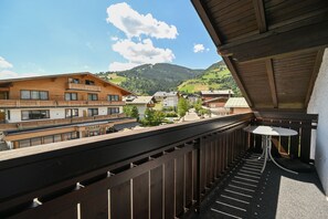 Ein Balkon mit Blick auf ein Dorf, Holzbauten und einen Berg im Hintergrund.