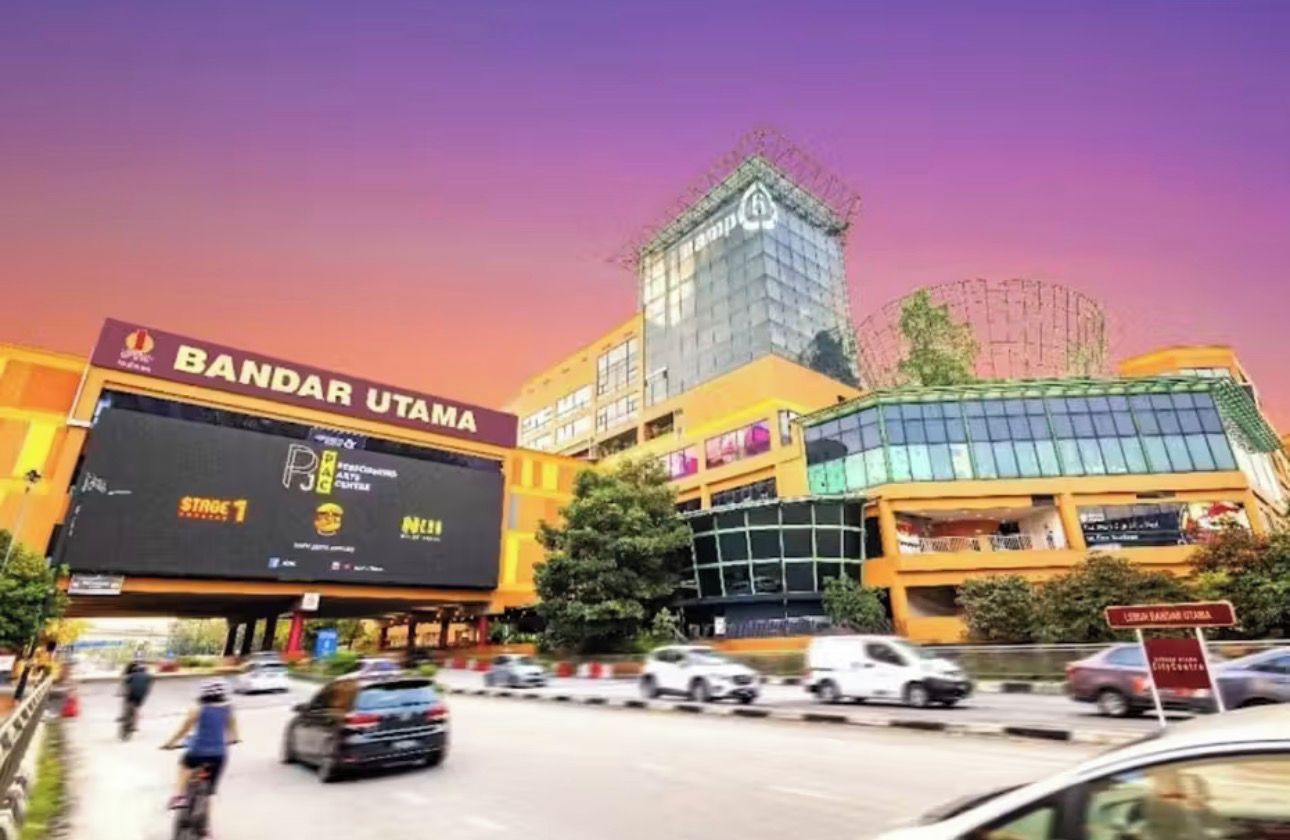 Un immeuble à plusieurs étages sur lequel est apposée une grande enseigne publicitaire indiquant « BANDAR UTAMA » et « Étape 1 ».