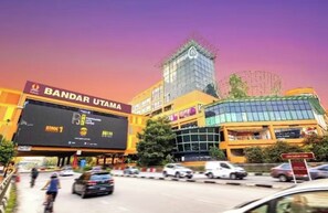Un immeuble à plusieurs étages sur lequel est apposée une grande enseigne publicitaire indiquant « BANDAR UTAMA » et « Étape 1 ».