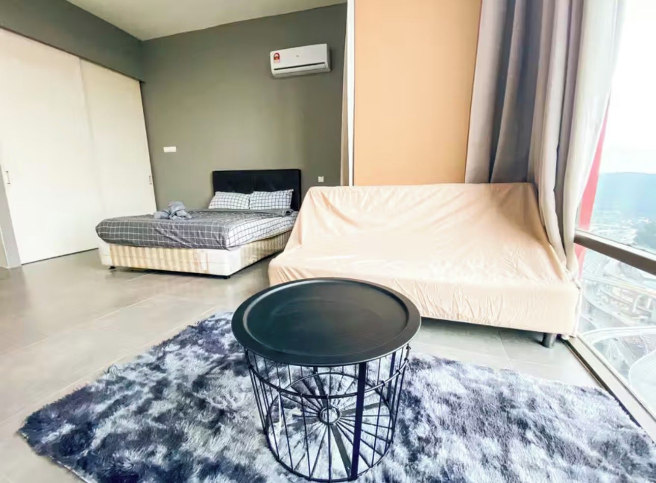 A modern bedroom with a bed, a sofa, a round table, and a view of the city.