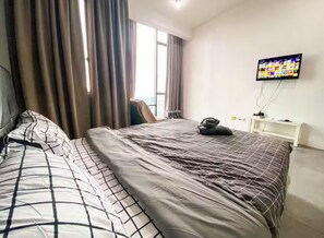 Ein Hotelzimmer mit Bett, Vorhängen, einem Fernseher und einem weißen Nachttisch.
