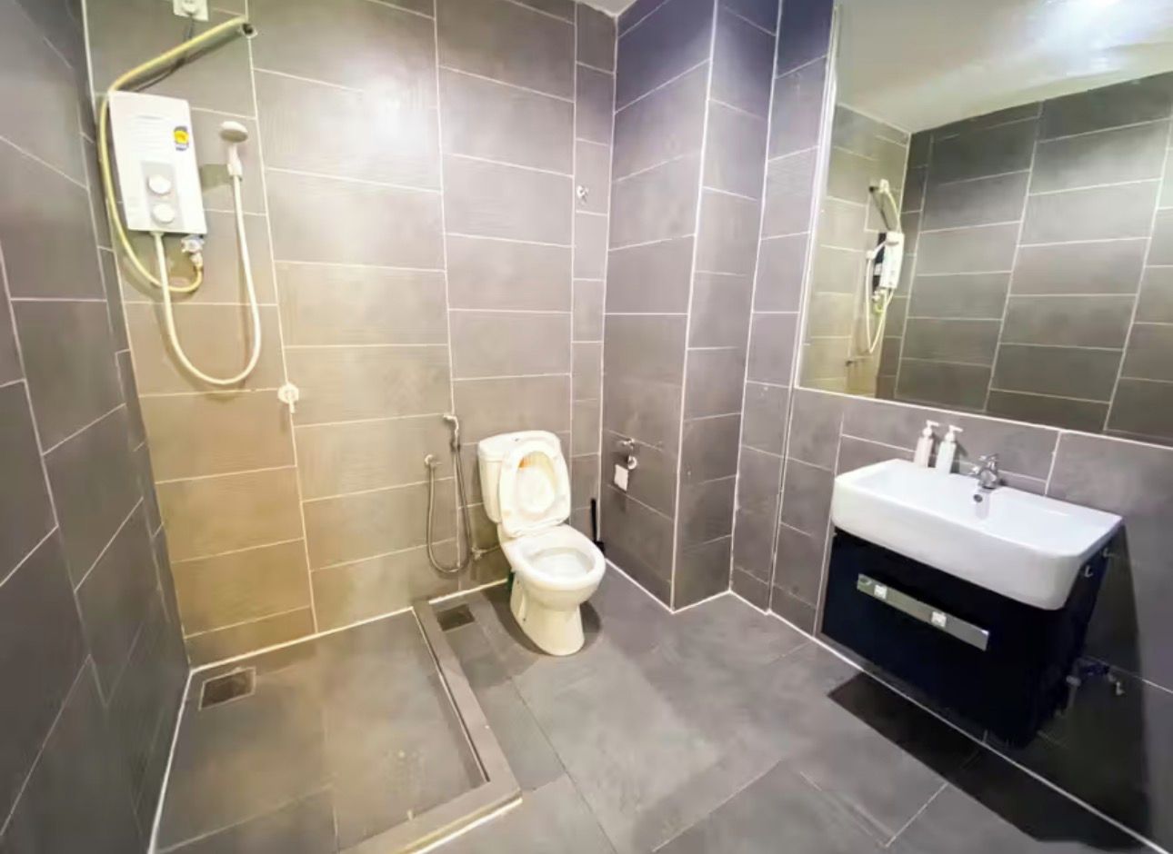 A modern bathroom with a toilet, shower, and sink.