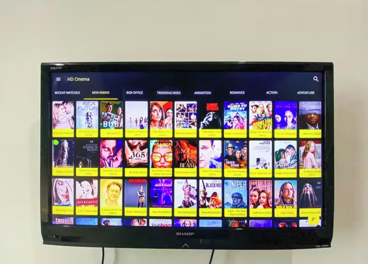 A flat-screen TV displaying a movie streaming interface with various categories and movie thumbnails.