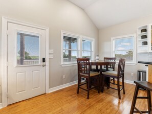 A dining area with a round table and four chairs, a white door, and a window with blinds. - 7 Palms-3 bed/3 bath waterfront escape w/boat ramp (Sargent)