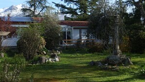 Ein Haus mit Garten, einer Steinstatue und einem Berg im Hintergrund.