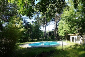 Piscina rodeada por árvores e uma área cercada.