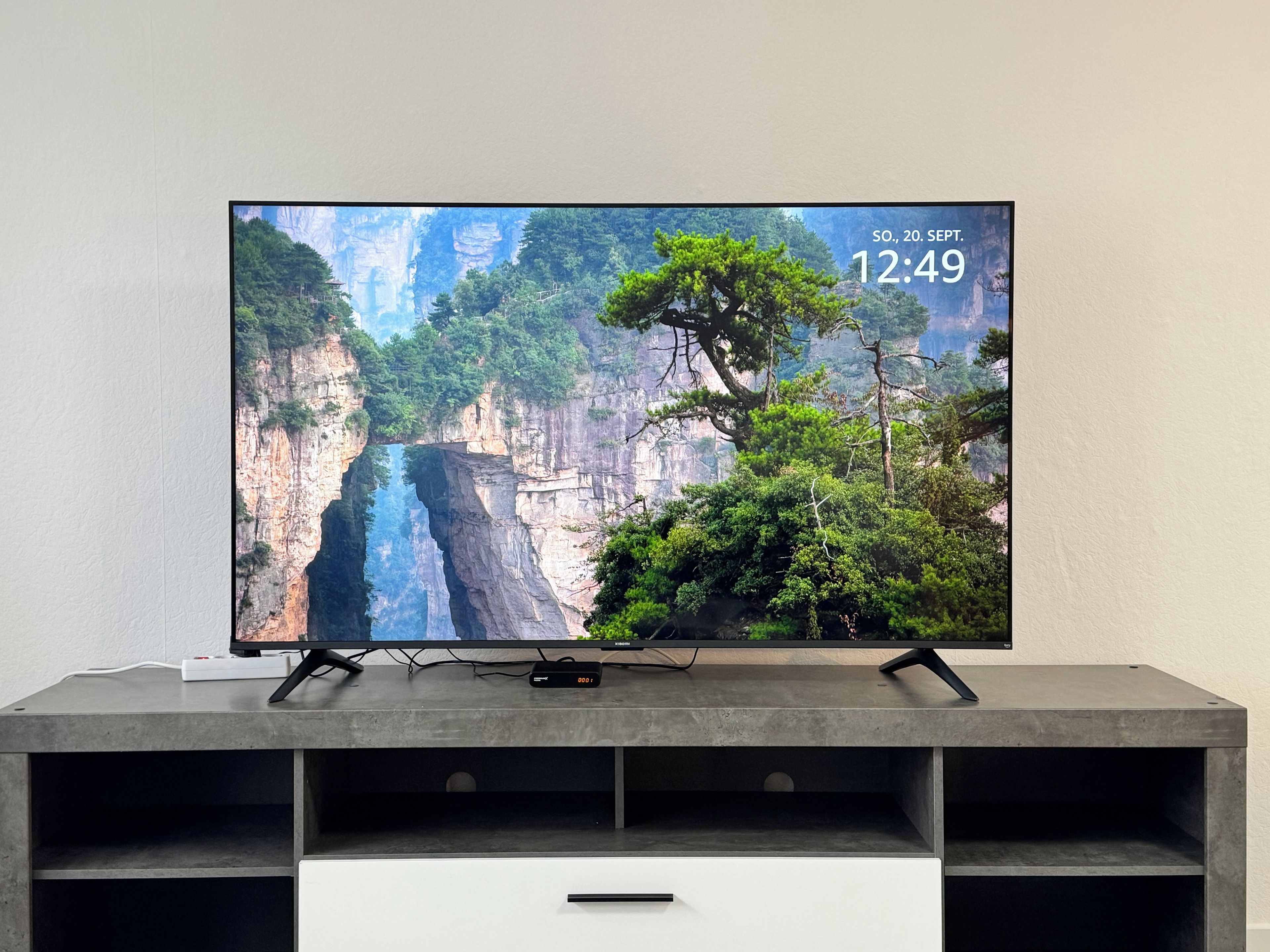 A flat-screen TV on a modern, minimalist entertainment unit with a mountainous landscape wallpaper.