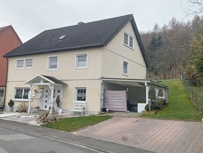 A two-story house with a front porch, a covered driveway, and a small garden area. - A Break in the Reinhardswald - Knickhagen Vacation Rental (Fuldatal)