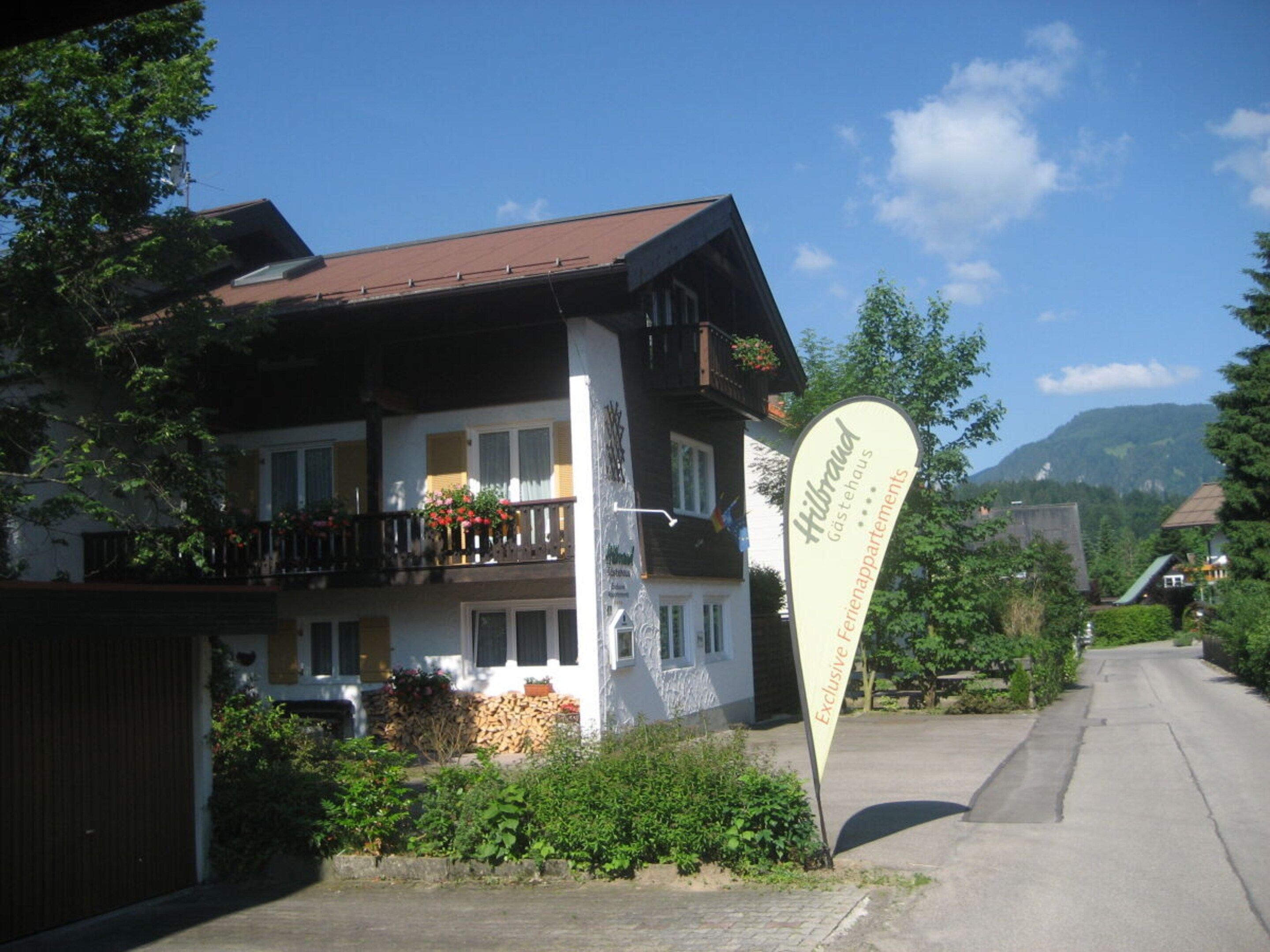 A hotel with a balcony, a signboard, and a view of the surrounding area.