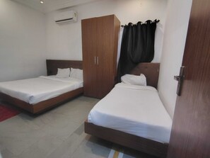 A room with two single beds, a wardrobe, and an air conditioning unit.
