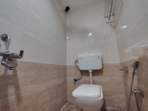 A bathroom with a toilet, a shower, and a handrail.