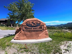 A sign for Moose Hollow Luxury Condominiums with a moose and trees graphic. - Ski Condo and Summer Resort (Eden)