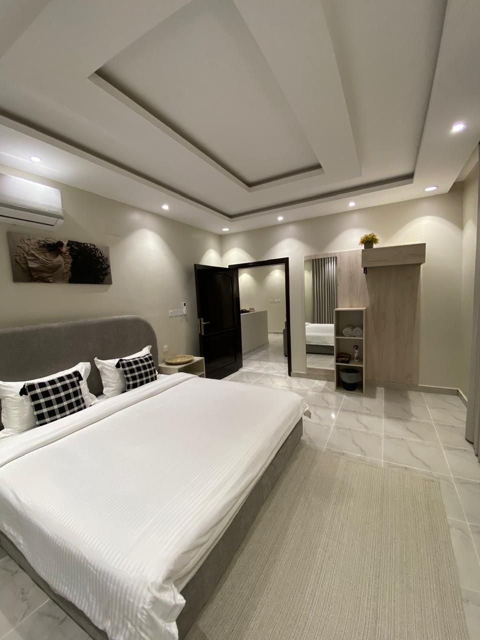 Ein modernes Schlafzimmer mit einem großen Bett, einem begehbaren Kleiderschrank und einem Badezimmer mit Dusche und Toilette.