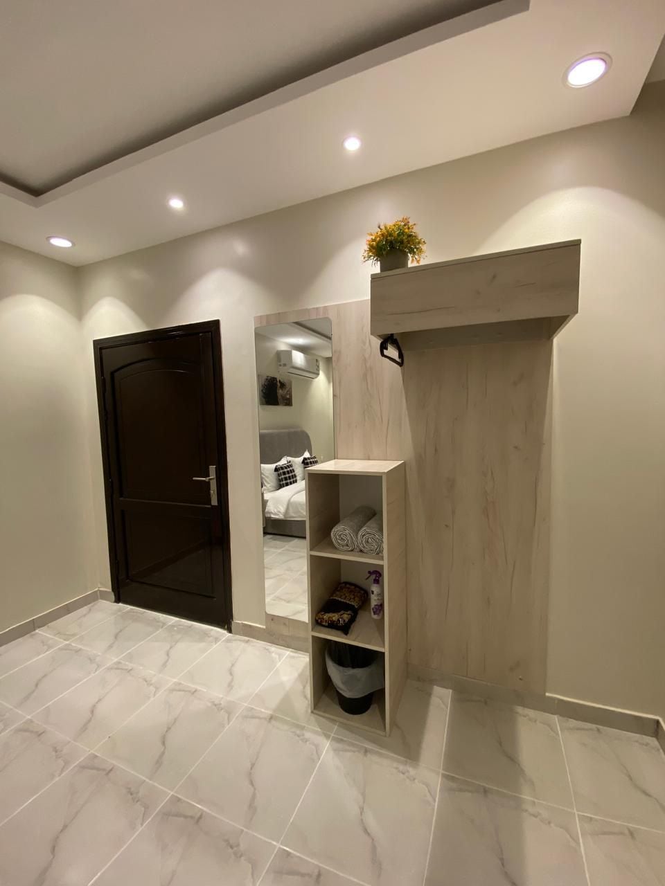 A hallway with a wooden cabinet, a door, and a tiled floor.