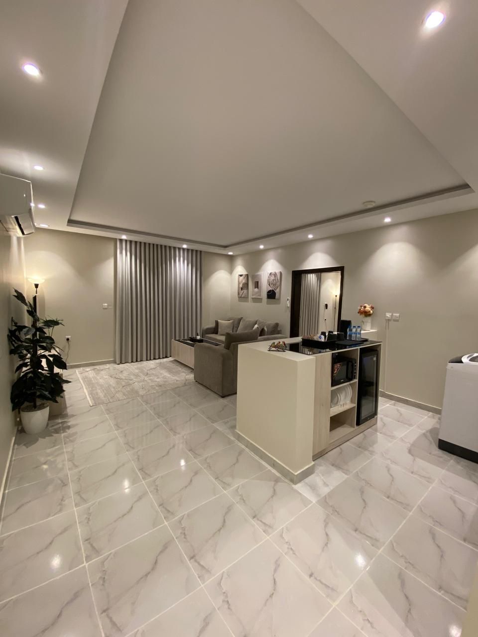 A modern living room with a high ceiling, a sofa set, a coffee table, and a small white cabinet.
