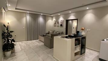 A modern living room with a high ceiling, a sofa set, a coffee table, and a small white cabinet.