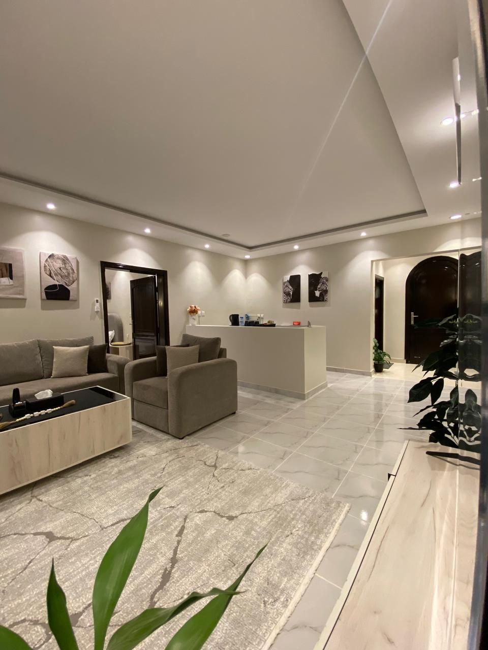 A modern living room with a sofa, coffee table, and a reception desk.
