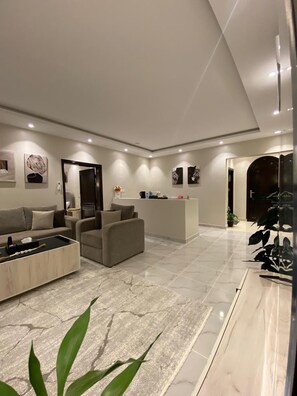 A modern living room with a sofa, coffee table, and a reception desk.